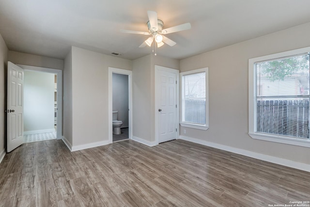 unfurnished bedroom featuring visible vents, light wood-style floors, a ceiling fan, ensuite bath, and baseboards