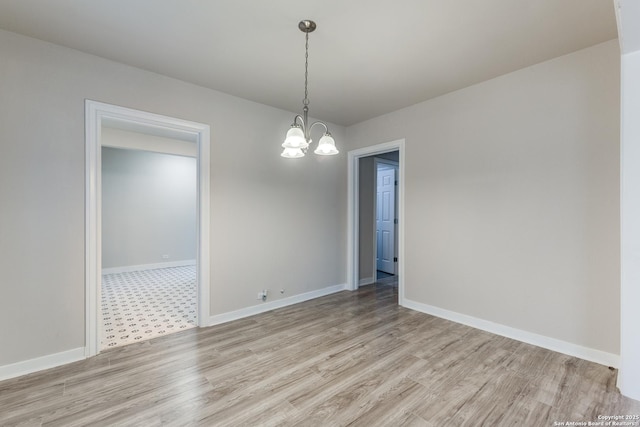 empty room with light wood-style floors, baseboards, and a notable chandelier