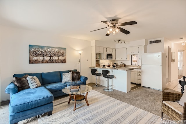 living area with a ceiling fan, light colored carpet, visible vents, and rail lighting