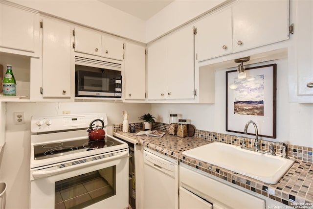 kitchen featuring tasteful backsplash, light countertops, white cabinets, a sink, and white appliances