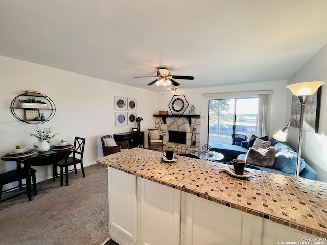 kitchen with ceiling fan, a fireplace, white cabinetry, open floor plan, and dark colored carpet