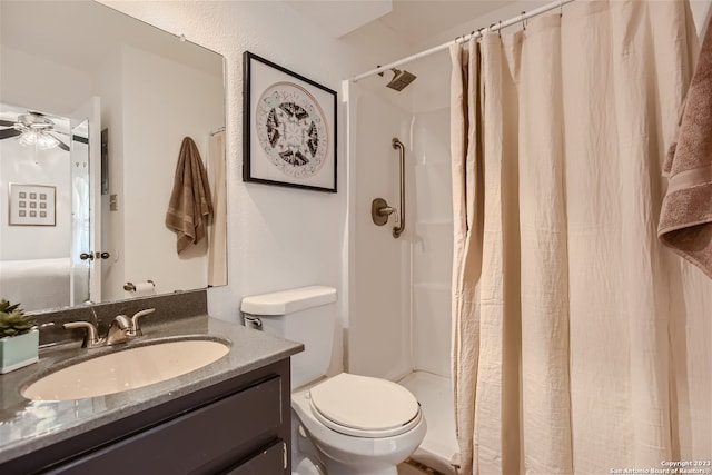 bathroom featuring toilet, ceiling fan, a shower stall, and vanity