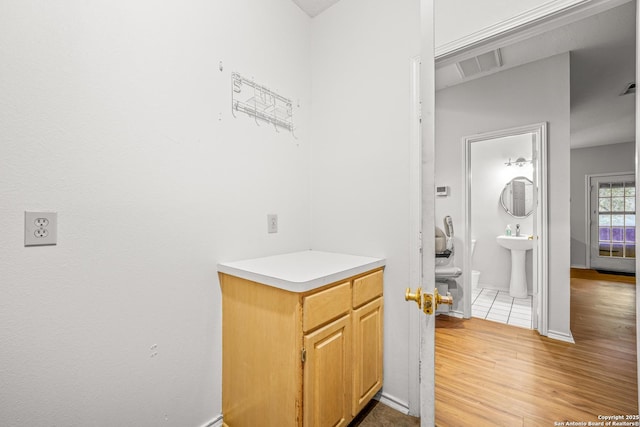 interior space featuring toilet, a sink, wood finished floors, visible vents, and baseboards