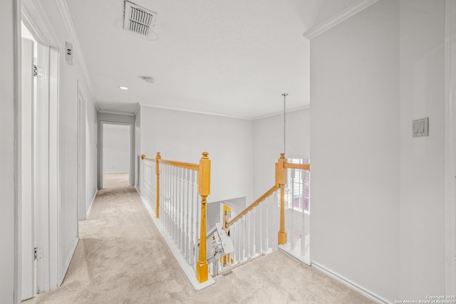 hallway featuring visible vents, light colored carpet, crown molding, and an upstairs landing