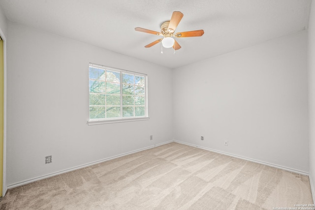 empty room featuring light colored carpet, ceiling fan, and baseboards