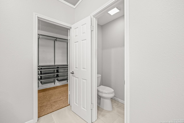 bathroom featuring toilet, baseboards, and tile patterned floors