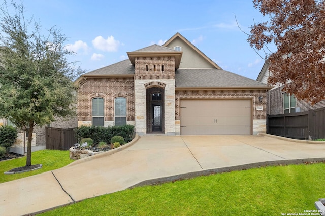 french country inspired facade with a garage, concrete driveway, brick siding, and fence