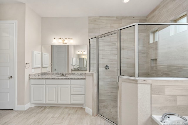 full bath with a bathtub, a stall shower, vanity, and wood finished floors