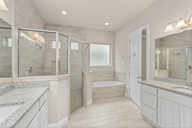 bathroom with a sink, a stall shower, two vanities, and a bath