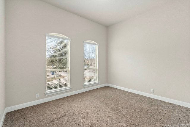 carpeted spare room featuring baseboards