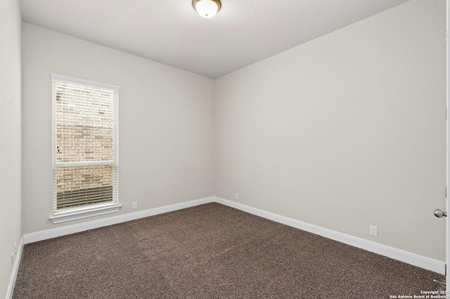 unfurnished room with baseboards and dark colored carpet