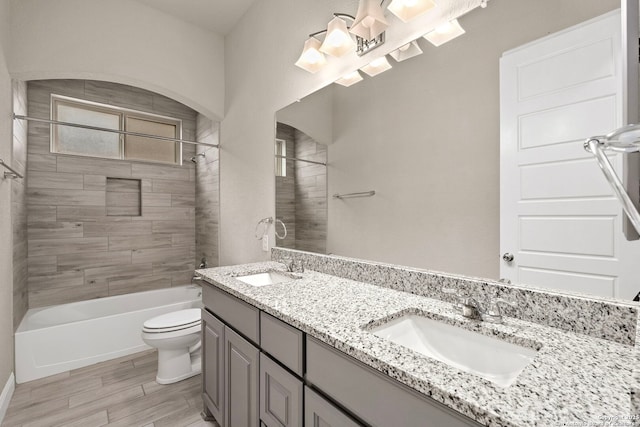 bathroom with double vanity, shower / tub combination, toilet, and a sink