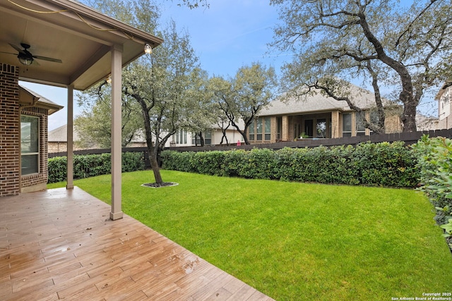 view of yard featuring a deck, fence, and a ceiling fan