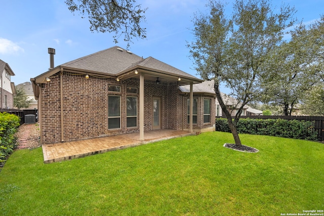 rear view of property with a yard, brick siding, a patio area, and central air condition unit