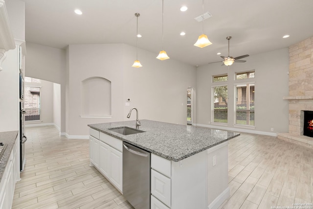 kitchen with stone counters, stainless steel appliances, a sink, white cabinetry, and open floor plan