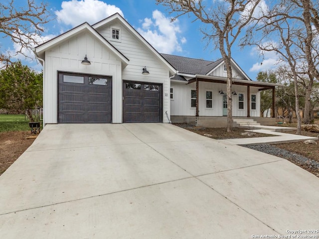 modern farmhouse with driveway, a shingled roof, an attached garage, covered porch, and board and batten siding