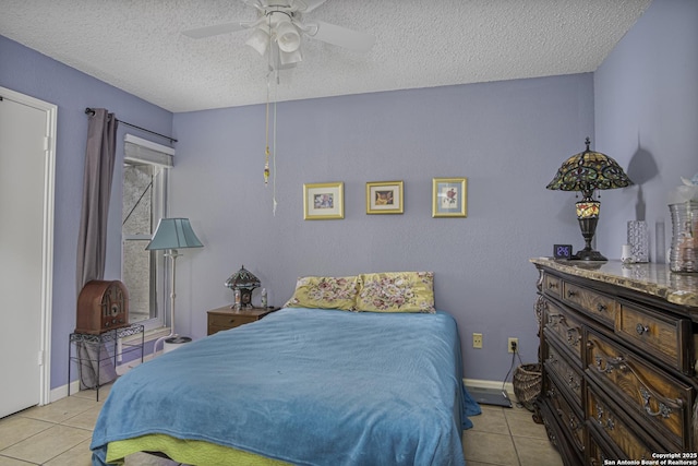 bedroom with a textured ceiling, light tile patterned flooring, a ceiling fan, and baseboards