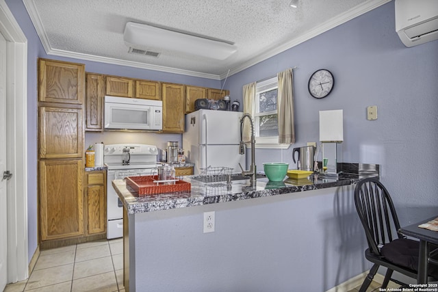 kitchen with white appliances, visible vents, brown cabinetry, a peninsula, and a wall mounted AC