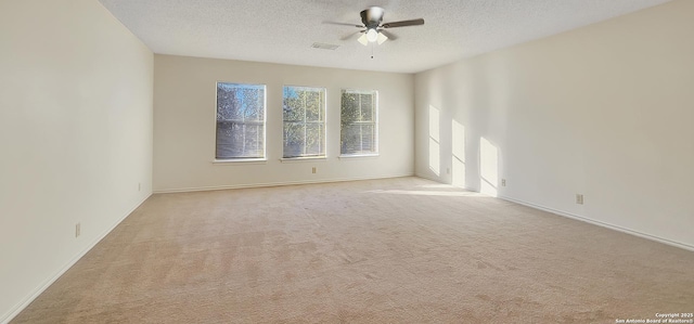 empty room with a textured ceiling, light carpet, visible vents, baseboards, and a ceiling fan