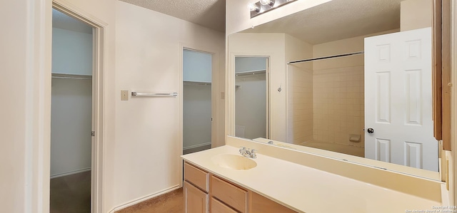 bathroom featuring a textured ceiling, a spacious closet, shower / bathing tub combination, and vanity