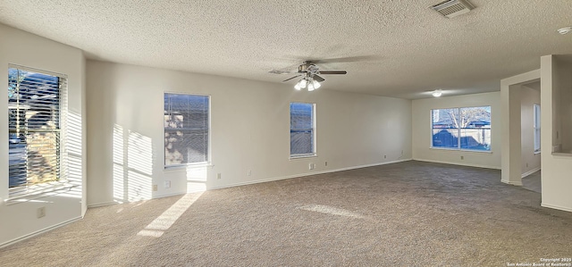 carpeted spare room featuring a textured ceiling, baseboards, visible vents, and a ceiling fan