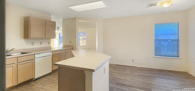 kitchen with light countertops, dishwasher, a sink, and light brown cabinetry