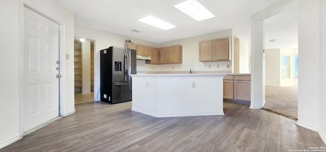 kitchen with under cabinet range hood, light brown cabinetry, light countertops, and stainless steel fridge with ice dispenser