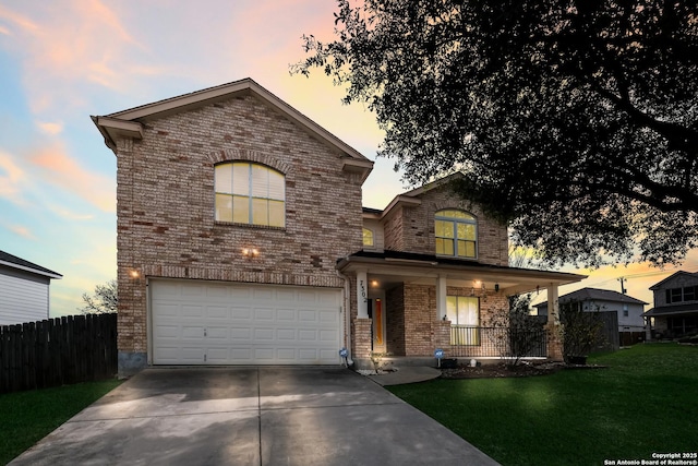 traditional home with a garage, brick siding, concrete driveway, covered porch, and a front yard