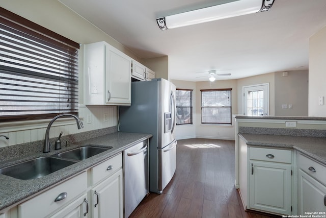 kitchen with dark wood-style flooring, stainless steel appliances, white cabinetry, a sink, and ceiling fan