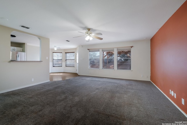 unfurnished living room with baseboards, carpet floors, visible vents, and a ceiling fan