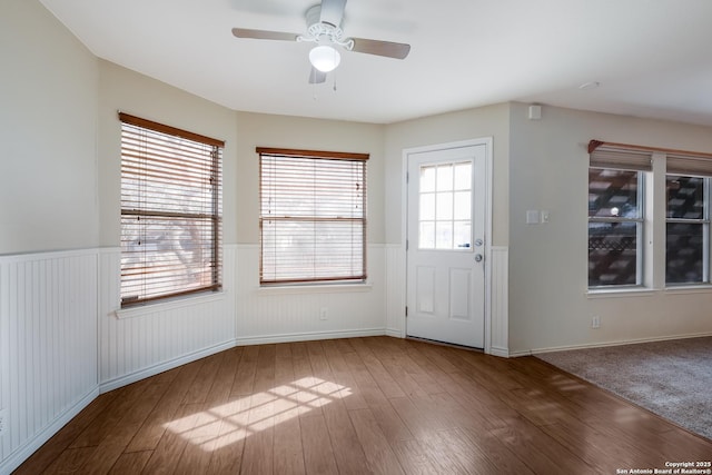 entryway with plenty of natural light, wood finished floors, and wainscoting