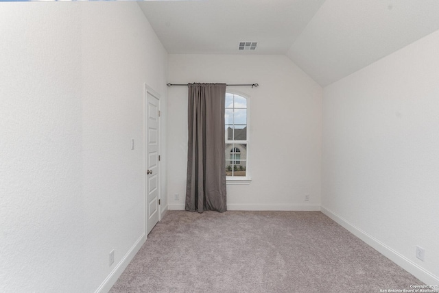 unfurnished room with light carpet, vaulted ceiling, visible vents, and baseboards