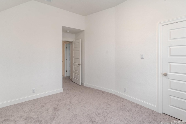 empty room featuring light carpet and baseboards