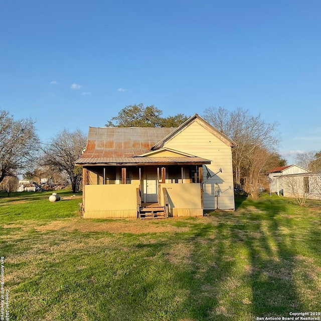 back of property featuring metal roof and a lawn