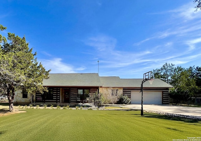 cabin featuring an attached garage, driveway, and a front lawn