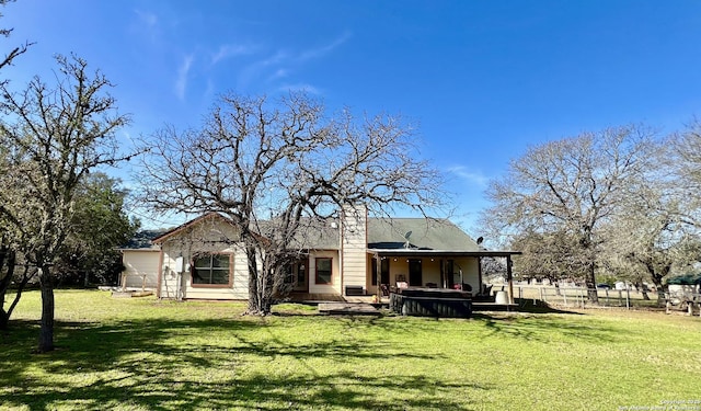 back of property with a lawn, a jacuzzi, a chimney, and fence