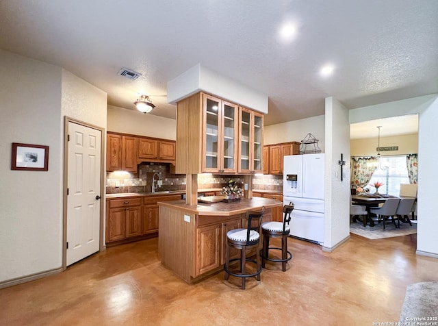 kitchen with visible vents, glass insert cabinets, a center island, white fridge with ice dispenser, and pendant lighting