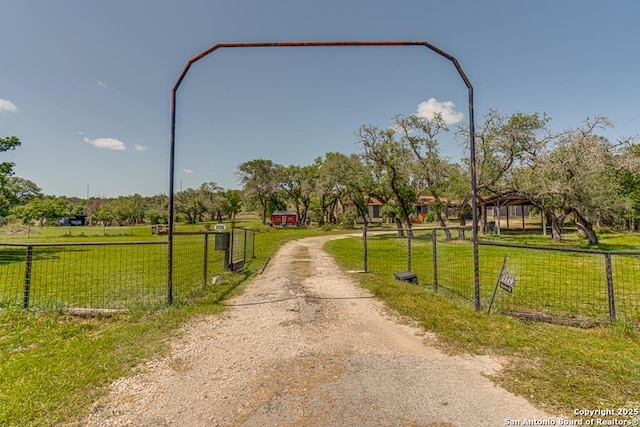 exterior space featuring a rural view, dirt driveway, fence, and a yard