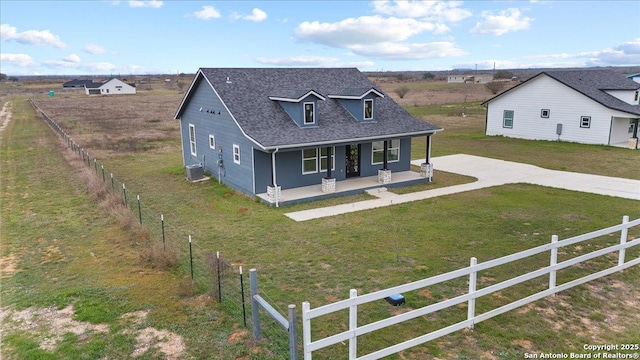 view of front of house with concrete driveway, a fenced front yard, roof with shingles, a porch, and a front yard