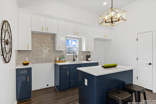 kitchen with white cabinets, a kitchen island, decorative light fixtures, light countertops, and a sink