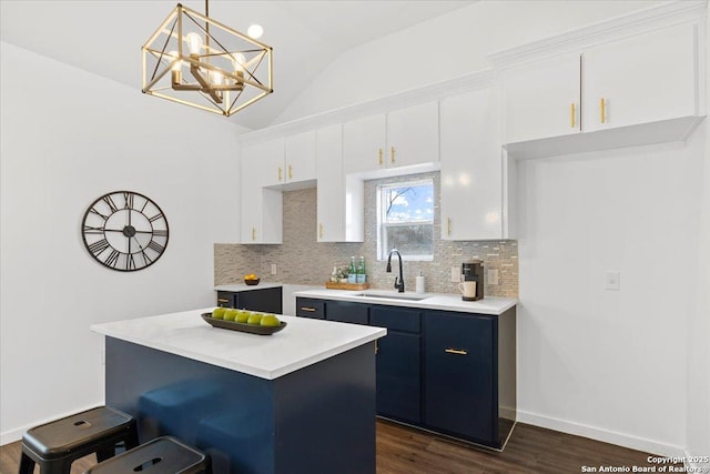 kitchen with a breakfast bar, a sink, white cabinetry, light countertops, and pendant lighting