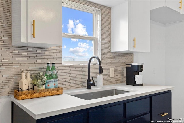 kitchen with light countertops, a sink, white cabinets, and blue cabinets