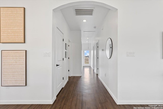 hall with attic access, arched walkways, visible vents, dark wood finished floors, and baseboards