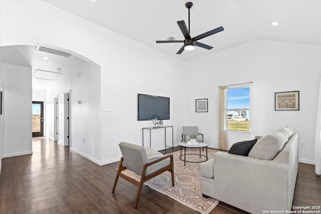 living room with arched walkways, dark wood-type flooring, a ceiling fan, visible vents, and attic access