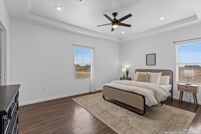 bedroom featuring dark wood-style floors, baseboards, and a tray ceiling