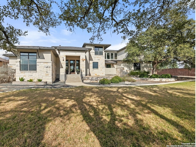 view of front of property featuring stone siding, fence, stucco siding, and a front yard