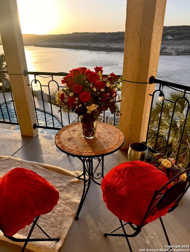 balcony at dusk featuring a water view