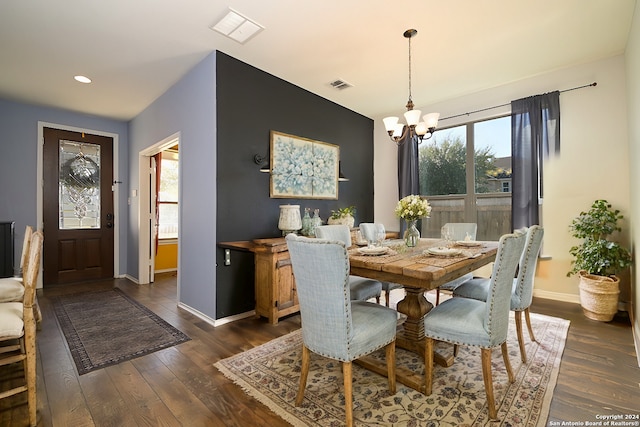 dining area with a chandelier, dark wood-style flooring, visible vents, and baseboards