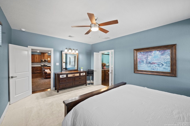 bedroom featuring a ceiling fan, ensuite bath, light colored carpet, and visible vents