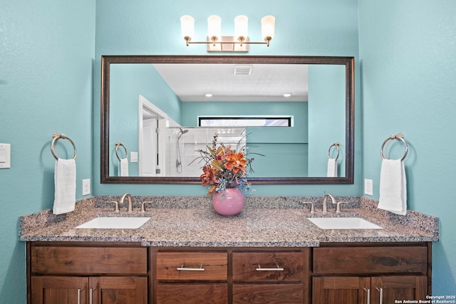 bathroom featuring double vanity, visible vents, a shower with door, and a sink